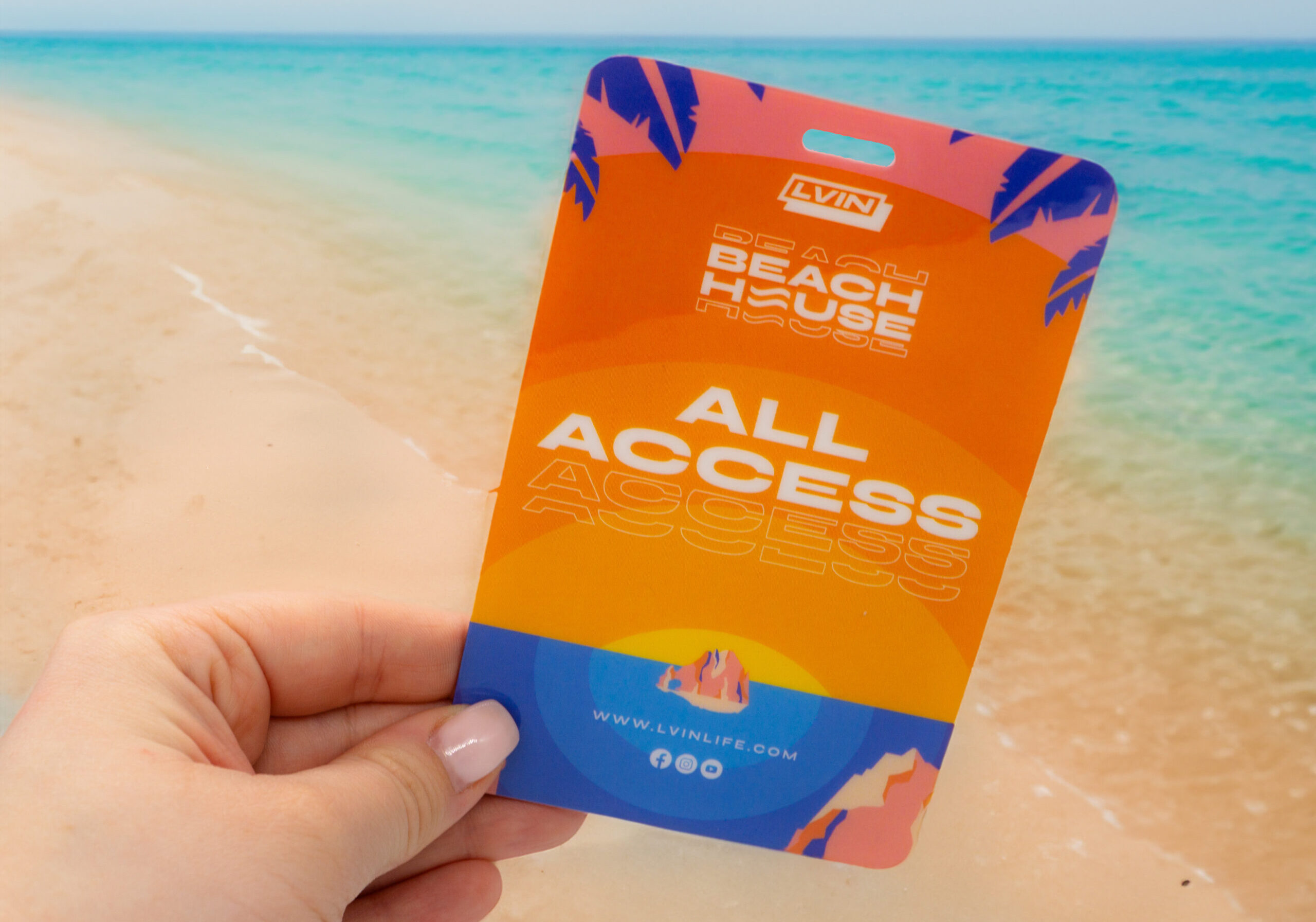All access pass being held out with a beach scene in the background